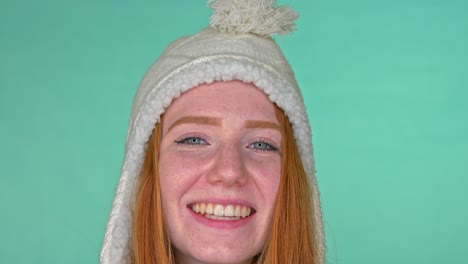 smiling redhead woman with blue eyes and warm winter hat on head