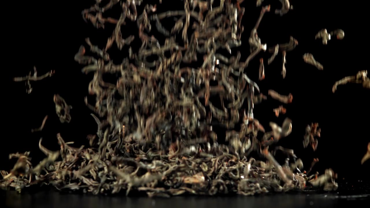 Dried Tea Leaves Falling in Slow Motion on Black Background