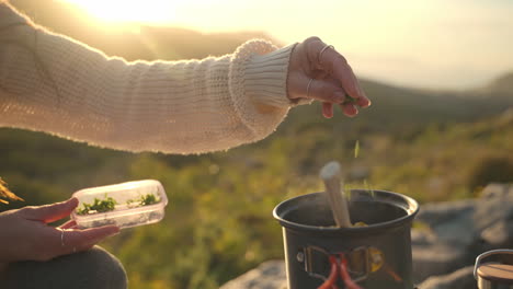 Nahaufnahme-Einer-Frau,-Die-Bei-Sonnenuntergang-In-Einem-Schwarzen-Topf-Auf-Einem-Berg-Essen-Kocht