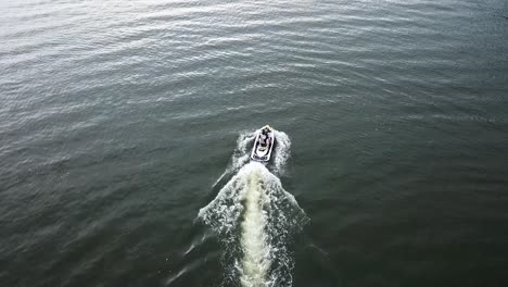 aerial follow of a watercraft moving at a high rate of speed through an open green lake in florida