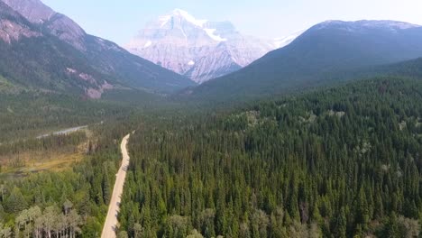 ascending aerial drone shot of wilderness, mountains as a road cutting through the forest