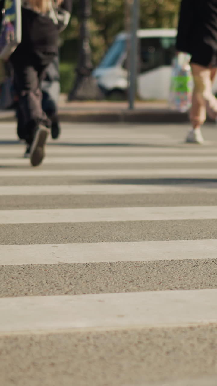 pedestrian and bicycle wheels crossing crosswalk busy city morning, commuters in sneakers and backpacks, cyclist weaving between walkers, bike tire shadows over zebra stripes, ambient traffic