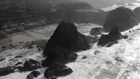 Aerial-view-over-rough-ocean-and-waves-crashing-on-Seal-Rock,-Oregon