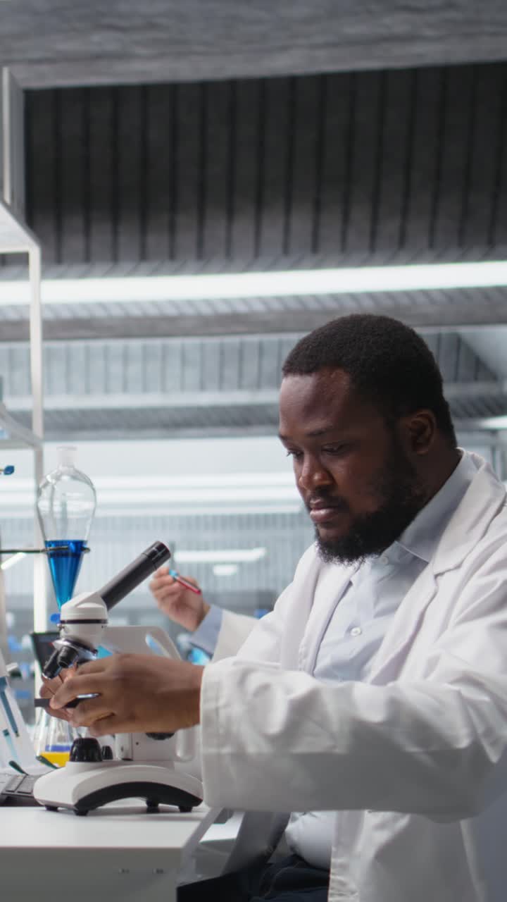 Vertical video Researcher operating compound microscope, doing sample observation