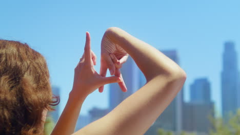 unknown girl showing sign la by fingers closeup. woman standing in summer park.