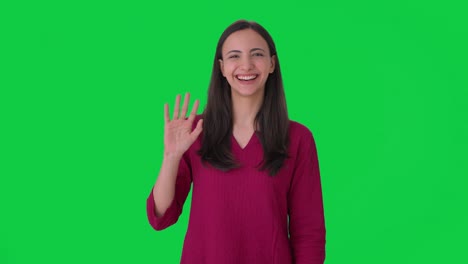 happy indian girl waving hi to the camera green screen