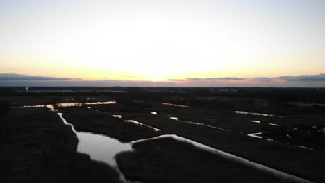 Field-Surrounded-By-Water-Ponds-At-Dusk-During-Winter-Season