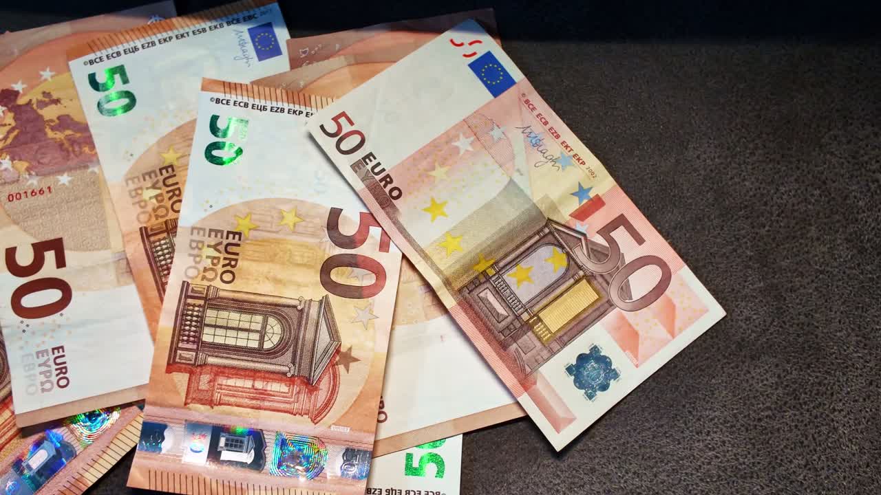 Flere femti euro-sedler spredt på mørk bakgrunn av et teppe