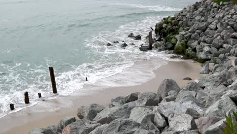 Waves-crashing-on-wooden-sticks-and-rocks