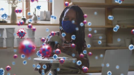 composite video of covid-19 cells floating against female potter making a pot on pottery wheel