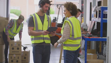 Trabajadores-Masculinos-Y-Femeninos-Que-Usan-Auriculares-En-Un-Almacén-De-Distribución-Logística-Usando-Una-Tableta-Digital