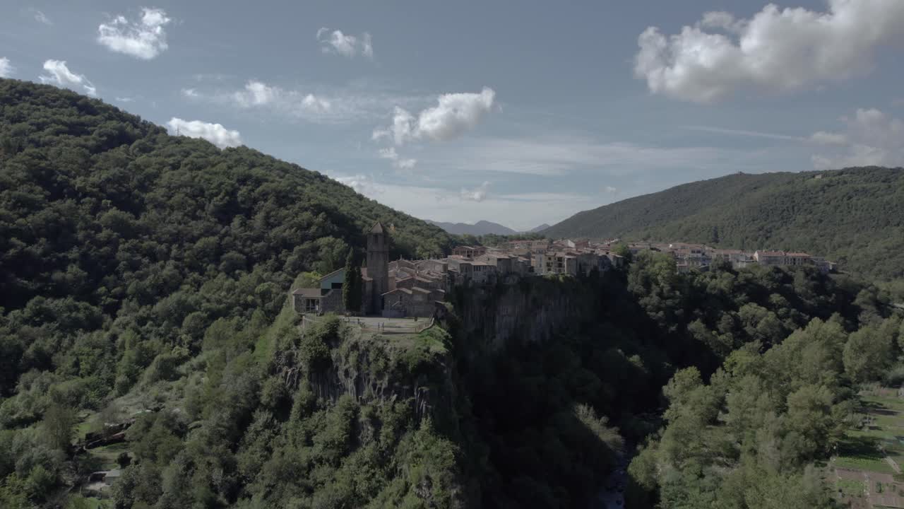 Drone's panoramic video showcases the breathtaking beauty of Castellfollit de la Roca, Spain: medieval village perched atop a striking volcanic cliff