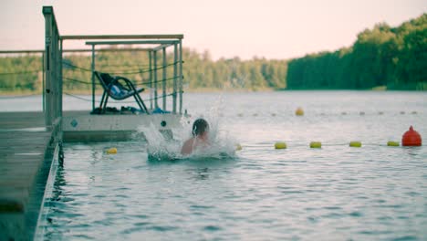 young boy with swimwear jumps into the water from the wooden pier