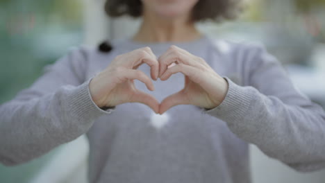 foto recortada de una mujer haciendo forma de corazón con las manos