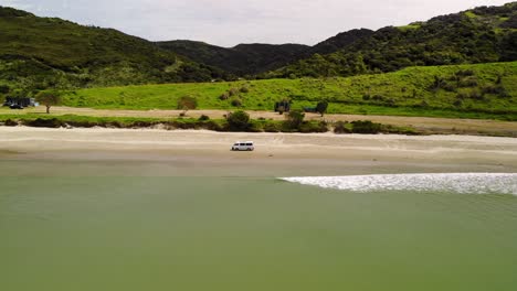 drone aerial of van driving on sandy beach at new zealand coast