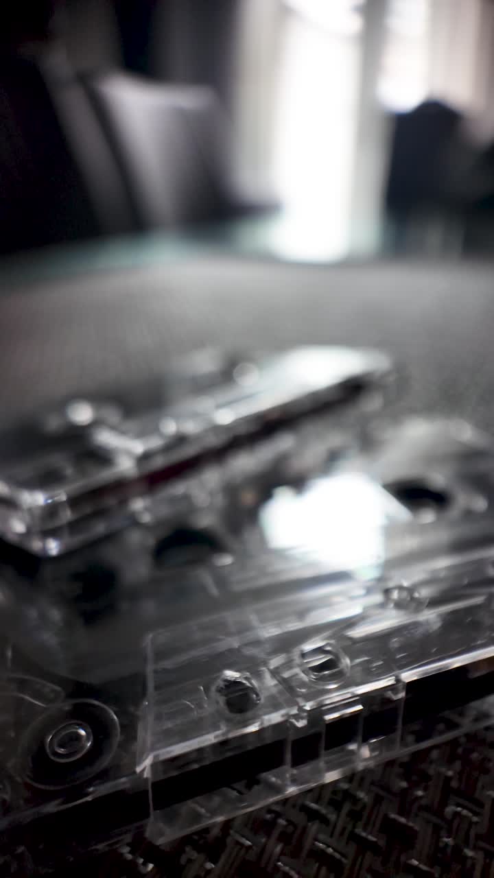 Transparent cassette tape playing back music, evoking nostalgia and retro audio technology.macro shot, vertical video
