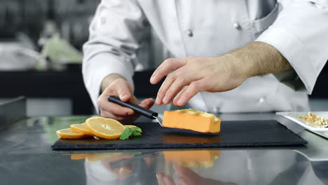 chef putting desert on board in professional kitchen