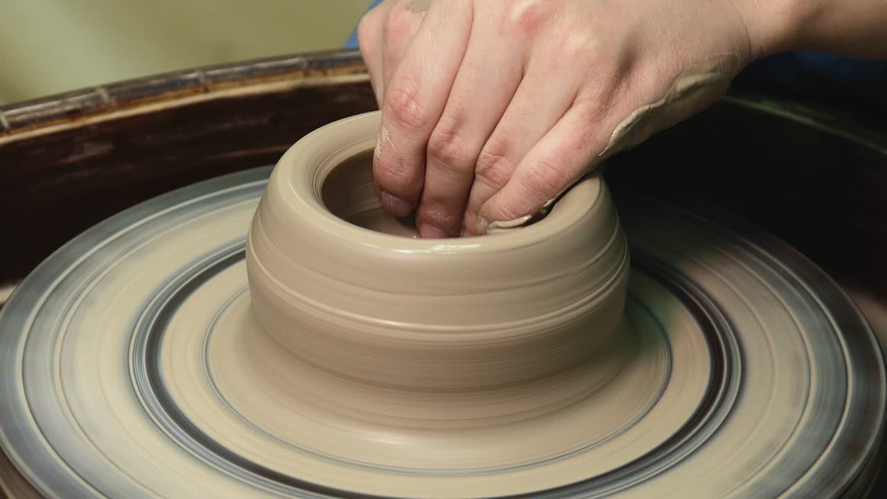 las manos de la mujer en la rueda de la cerámica. el artesano el artista da forma a la olla