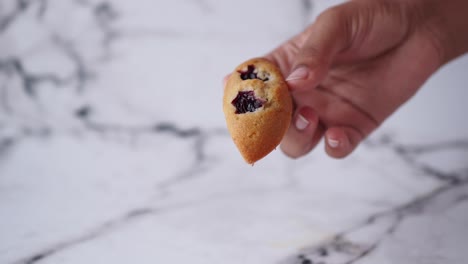 mano sosteniendo un pastel pequeño lleno de cereza