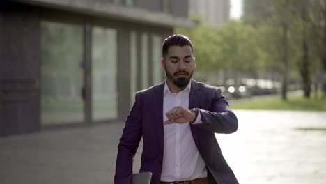 serious businessman with laptop running on street