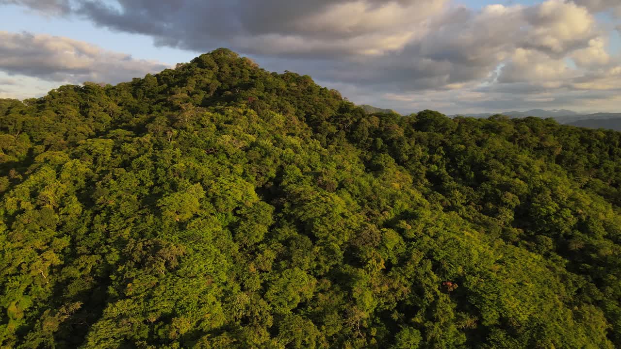 drone de 4k volando hacia atrás mientras se desplaza hacia los lados revelando una impresionante puesta de sol sobre un paisaje remoto cubierto de exuberante selva tropical