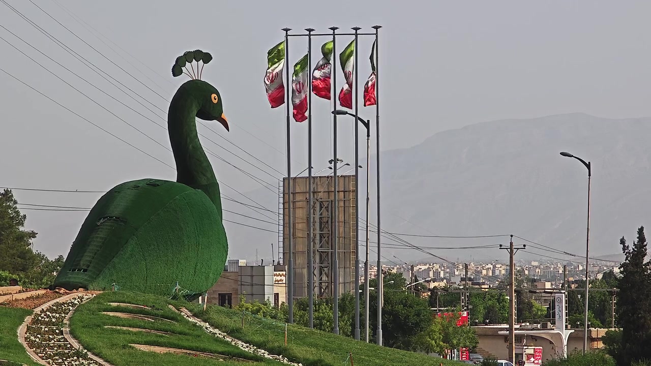 市立公園にある、なびくイランの国旗を伴う大きなクジャクのトピアリー彫刻。