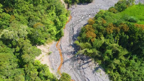 Toma-Aérea-De-Un-Dron-Descendiendo-Sobre-Un-Remoto-Lecho-De-Río-Seco-Rodeado-De-árboles-Forestales,-Risaralda,-Colombia