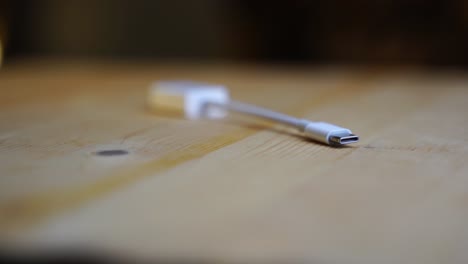 white-cable-adapter-from-old-usb-to-new-USB-C-on-a-wooden-board-rotates