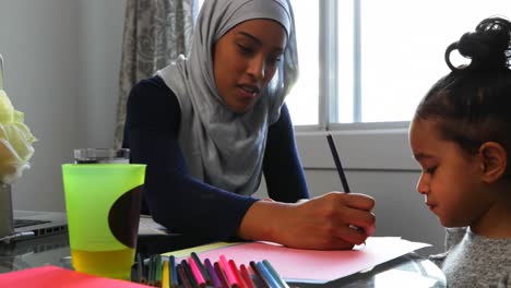 Young-mother-helping-her-daughter-with-homework-on-table-at-home-4k