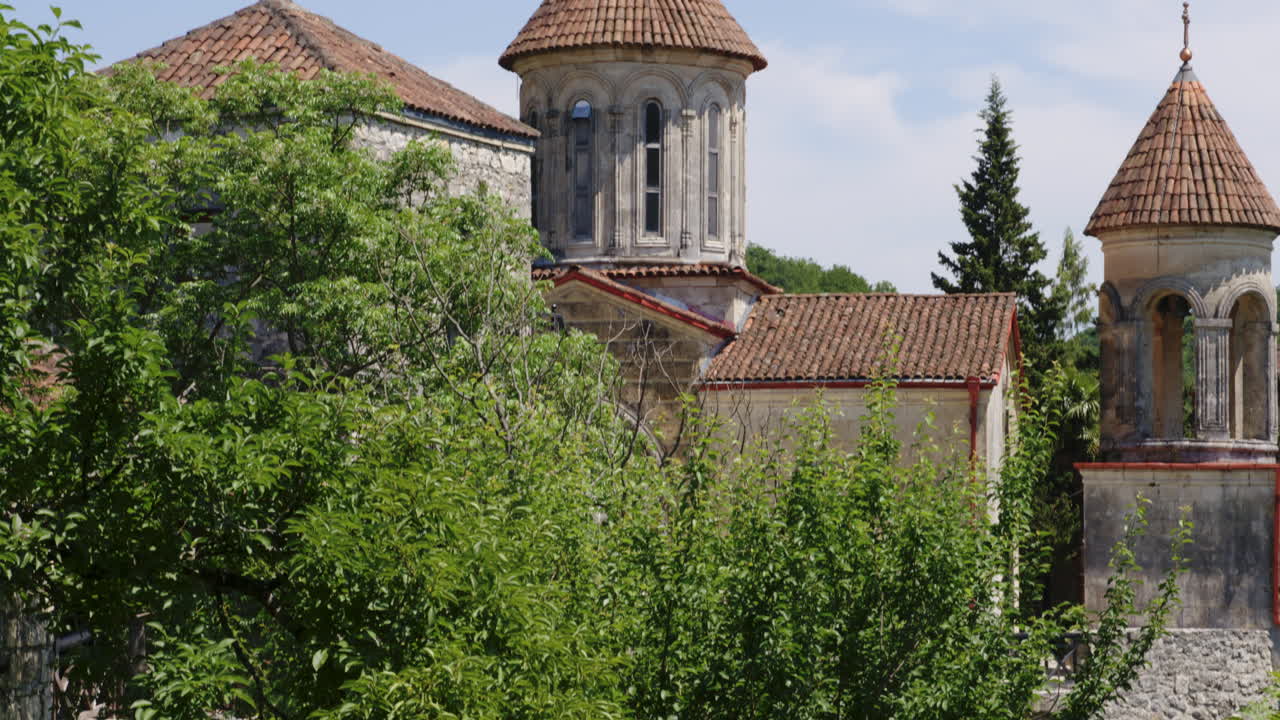 моцаметский православный монастырь за листвой кустарников в солнечный день, грузия