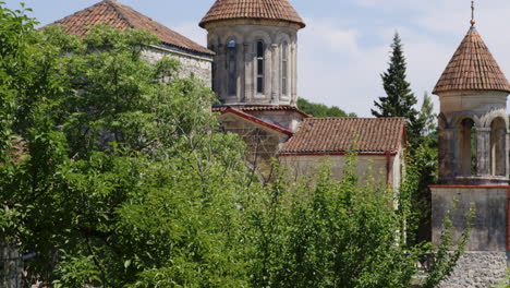 monasterio ortodoxo motsameta detrás de frondosos arbustos en un día soleado, georgia