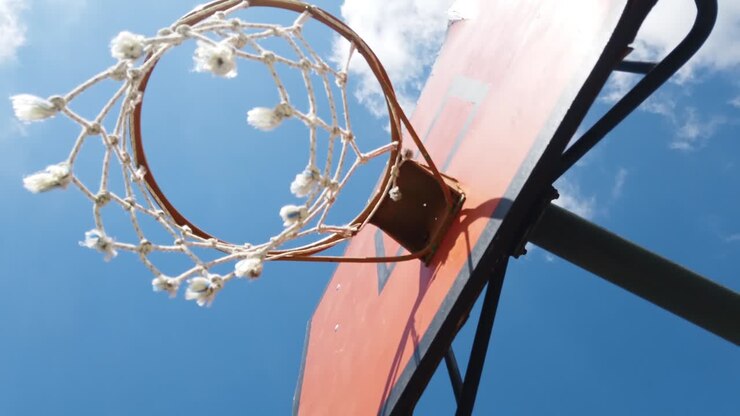 Canestro da basket visto da sotto in una giornata di sole contro il cielo blu
