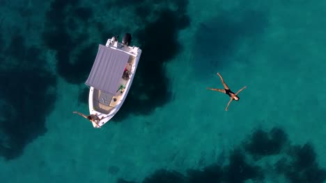 young couple enjoying turquoise paradisiacal sea waters with a boat