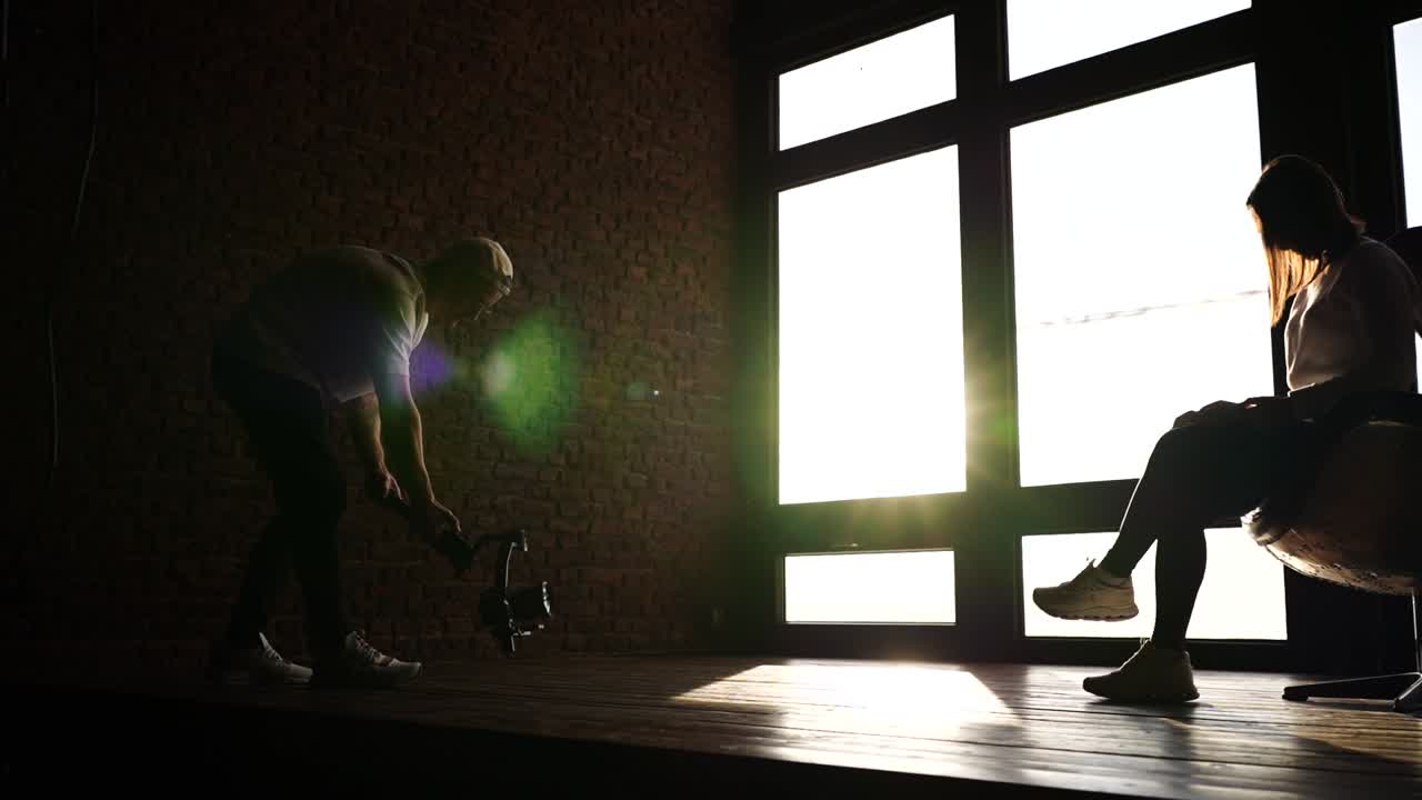 비디오 촬영자는 밝은 창 근처의 모델을 촬영하기 위해 기발 안정화 장치에 카메라를 사용합니다.