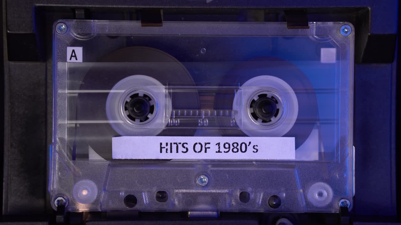 de los éxitos de la década de 1980 cinta de cassette de audio con compilación de música jugando en el reproductor de cubierta estático de cerca 4k