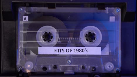 de los éxitos de la década de 1980 cinta de cassette de audio con compilación de música jugando en el reproductor de cubierta estático de cerca 4k