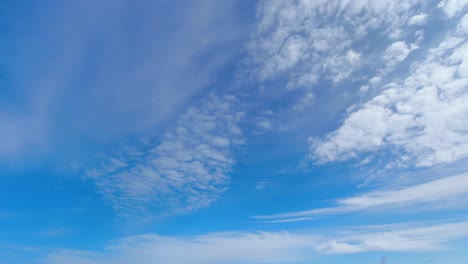 wispy clouds roll across pale blue sky in spacious nature background