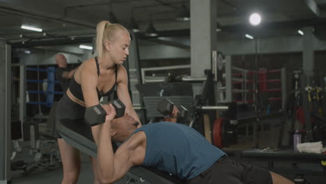 caucasian female monitor and an athletic african american man in the gym.