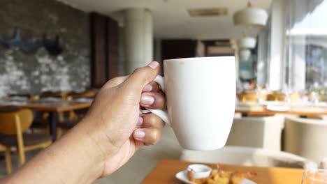 hand holding a coffee cup in a restaurant