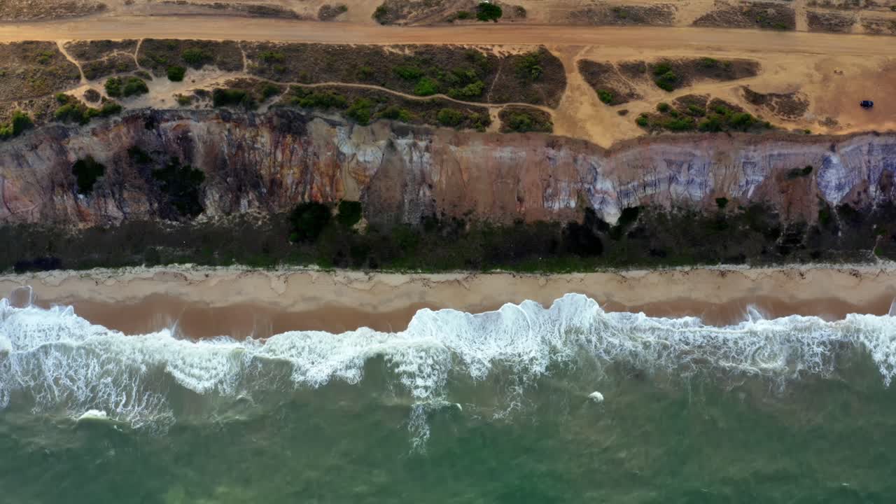 Gorgeous aerial drone left trucking shot of a large cliff dropping straight to the beach and ocean at the tropical Sun beach near Joao Pessoa, Brazil on a warm summer evening