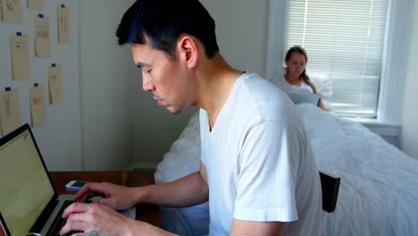 man using laptop while woman using digital tablet