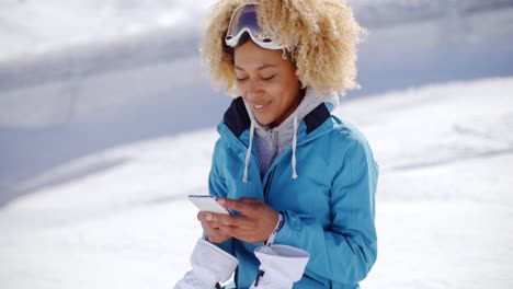 mujer en traje de nieve comprobando el teléfono