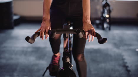 Sección-Media-De-La-Mujer-Haciendo-Ejercicio-En-Bicicleta-Estática-En-El-Gimnasio