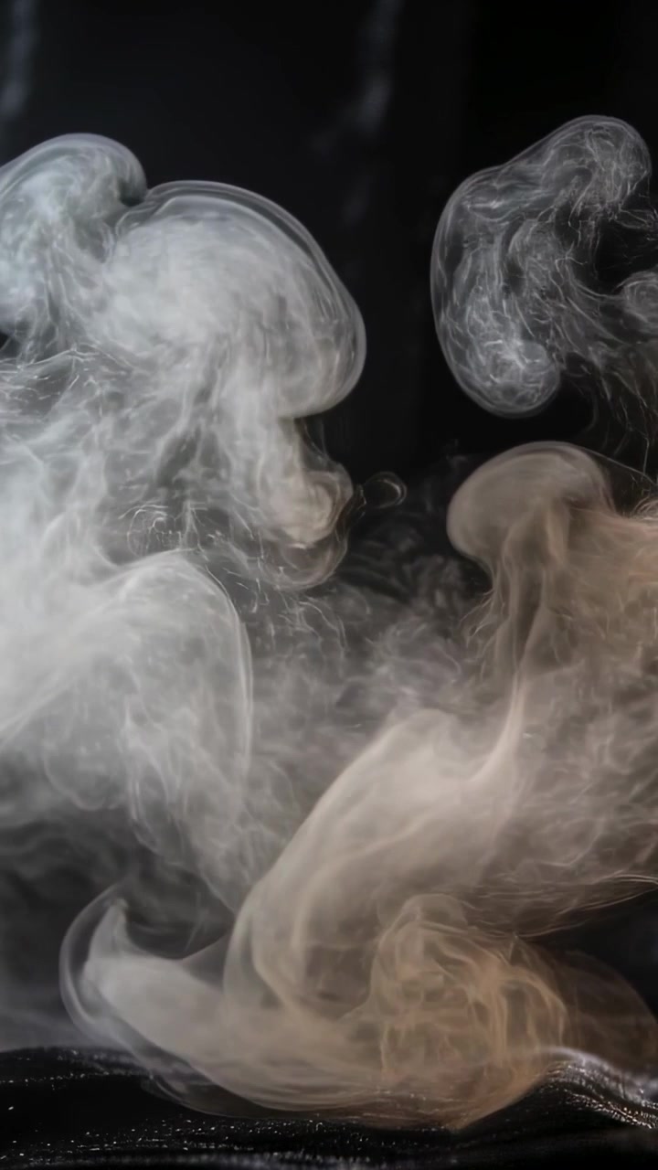 Vertikales Video: Aus niedrigem Tuch aufsteigender weißer Nebel kräuselt sich vor einer schwarzen Platte durch die Luft.