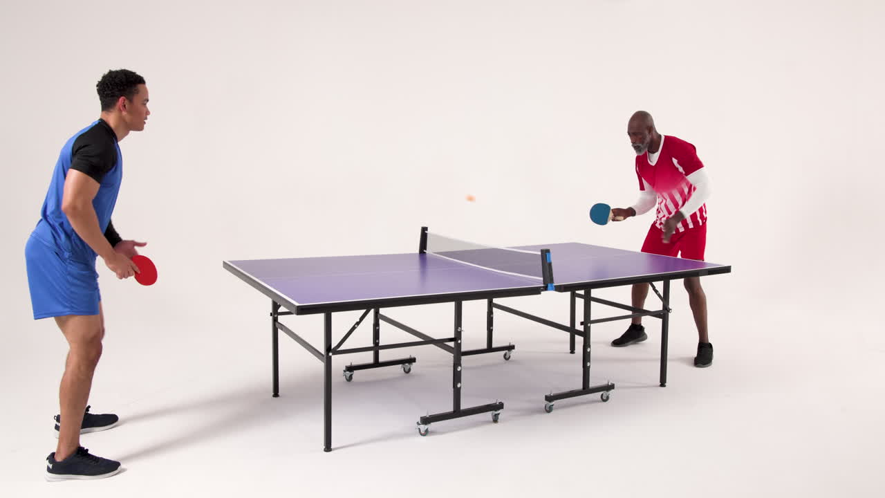 Playing table tennis, two men competing in friendly match indoors