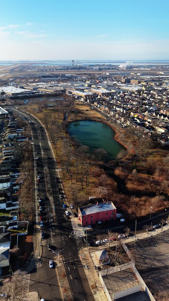 Vista aerea da drone nel Queens, New York, ripresa aerea ad alta angolazione che domina un parco con un laghetto in un quartiere residenziale del Queens, con l'aeroporto LaGuardia visibile in lontananza