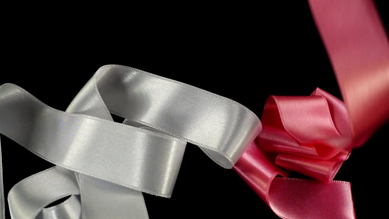 Satin ribbon on a black background. Slow motion