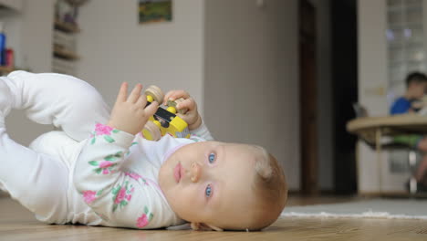 a baby girl in a romper suit lying on the floor