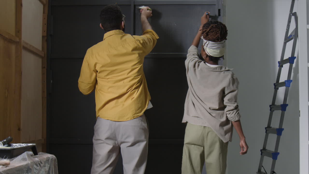 Two people painting a door together