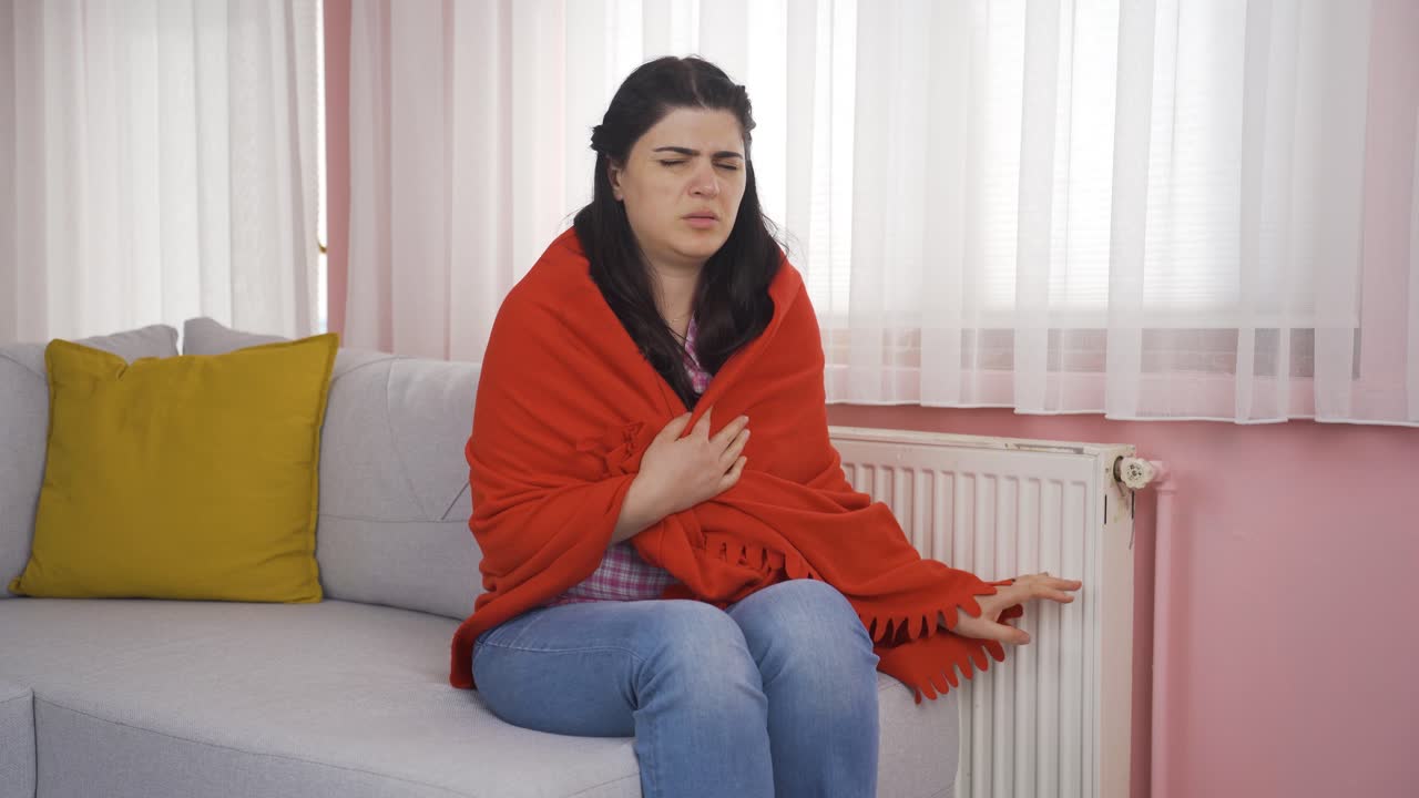 la mujer tiene frío y está tocando el calentador.